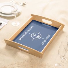 there is a tray with an anchor on it next to wine glasses and silverware