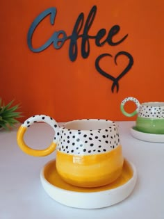 two yellow and green coffee cups sitting on top of a white plate next to each other