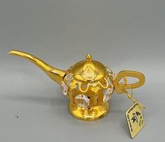 a gold teapot with a keychain attached to it