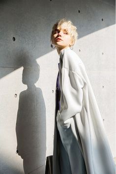 a woman standing in front of a wall with her shadow on the wall behind her