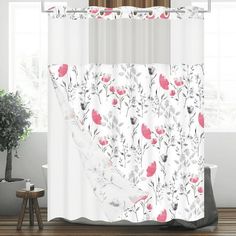 a white shower curtain with pink and grey flowers on it in front of a window