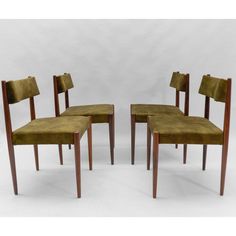 a set of four chairs with wooden legs and green velvet upholstered seat covers