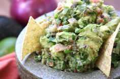 a bowl filled with guacamole and tortilla chips on top of it