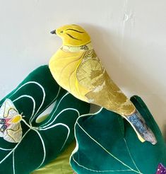 a yellow bird sitting on top of a green pillow