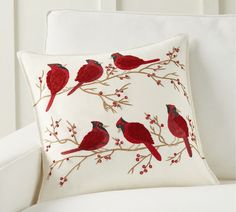 a white chair with a red cardinal pillow on it's back and the rest of its arm