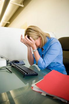 a woman sitting at a desk with her head in her hands