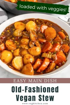 a bowl filled with stew and vegetables on top of a white plate next to a spoon