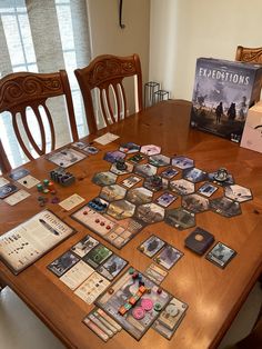 a wooden table topped with lots of cards and game pieces on top of each other