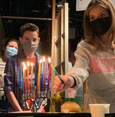 a woman wearing a face mask lights candles on a cake