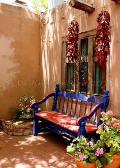 a wooden bench sitting in front of a building with potted plants on the ground