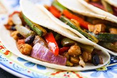 three tacos filled with meat, beans and veggies on a colorful plate