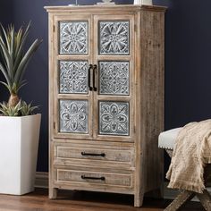 a wooden cabinet with metal panels on the doors and drawers next to a potted plant