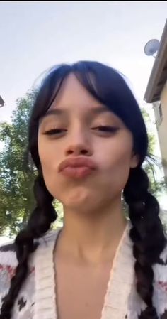 a woman with long hair making a funny face while standing in front of a house