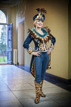 a woman dressed in leopard print and blue pants, standing next to a wall with an open doorway