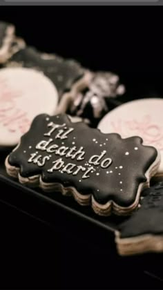 some cookies that are on top of a black tray with white frosting and writing