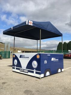 a blue and white bus parked in a parking lot with a canopy over the top