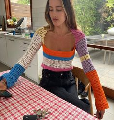 a woman sitting at a table with a cell phone in her hand and a pair of scissors on the table