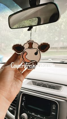 a person holding up a sticker with a cow on it's face in the car