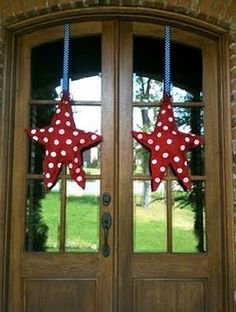 two red and white stars hanging from the side of a wooden door with glass panes