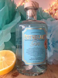 a bottle of pothecany gin on a wooden table next to a lemon