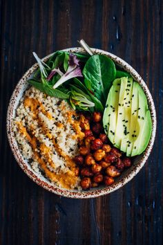 a bowl filled with rice, avocado and other food on top of a wooden table