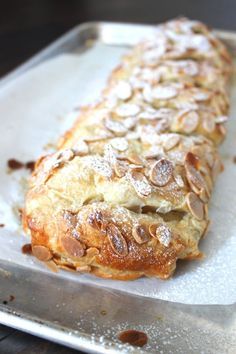 a pastry is sitting on top of a baking sheet with powdered sugar and almonds