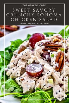 a white plate topped with salad covered in chicken and pecans next to a fork