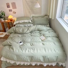 an unmade bed sitting next to a window in a room with a lamp on it