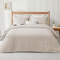 a bed with white comforter and pillows in a room next to a wooden headboard