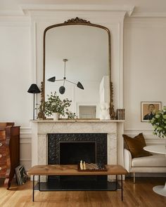 a living room filled with furniture and a fire place under a large mirror over a fireplace