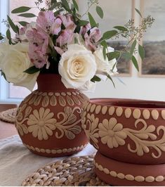 two vases with flowers in them sitting on a table