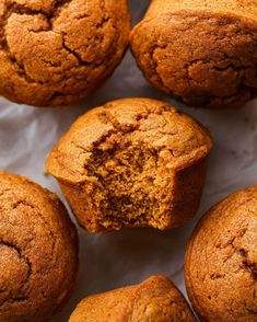 several muffins on a white surface with one cut in half to show the inside