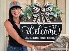 a woman holding up a welcome sign in front of a door