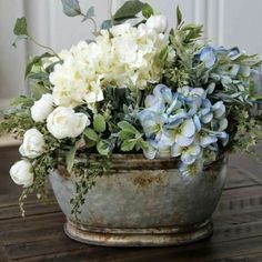 white and blue flowers are in an old metal bowl