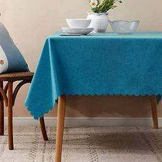 a blue table cloth with scalloped edges sits on a wooden chair in front of a white wall