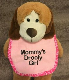 a stuffed dog wearing a pink bib with the words mommy's drooly girl on it