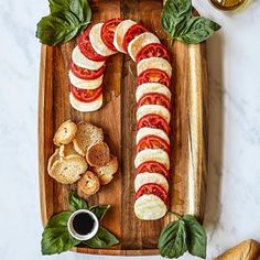 sliced tomatoes, mozzarella and basil on a wooden platter with garlic bread