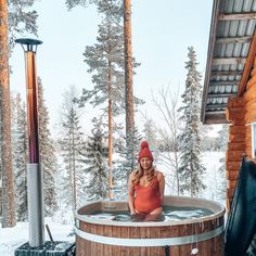 a woman in a red bathing suit is sitting in a hot tub with snow on the ground