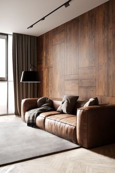 a brown leather couch sitting in front of a window next to a rug and lamp