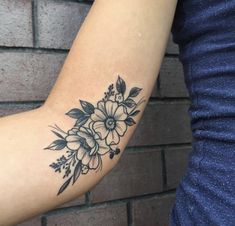 a woman's arm with black and white flowers on the left side of her arm