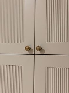 two white cupboards with brass handles and knobs on the doors are seen in this image