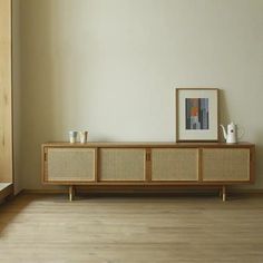 an empty room with a wooden cabinet and pictures on the wall