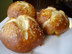 three hot cross buns with cheese on them sitting on a white plate, ready to be eaten