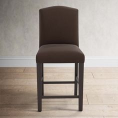 a brown chair sitting on top of a hard wood floor next to a white wall