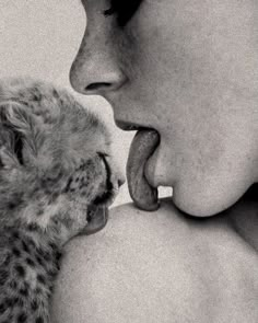 a woman holding a kitten up to her face with it's mouth open and tongue out