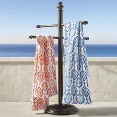 a towel rack with two towels hanging from it's sides next to the ocean