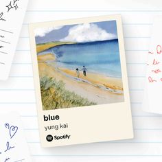 two people walking on the beach next to an open notebook with blue watercolors