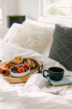 a tray full of food on top of a bed next to a cup of coffee