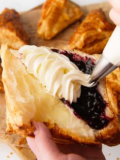 someone is spreading cream on top of a blueberry danish pastry with a butter knife