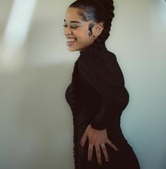 a woman in a black dress is smiling and holding her hands out to the side